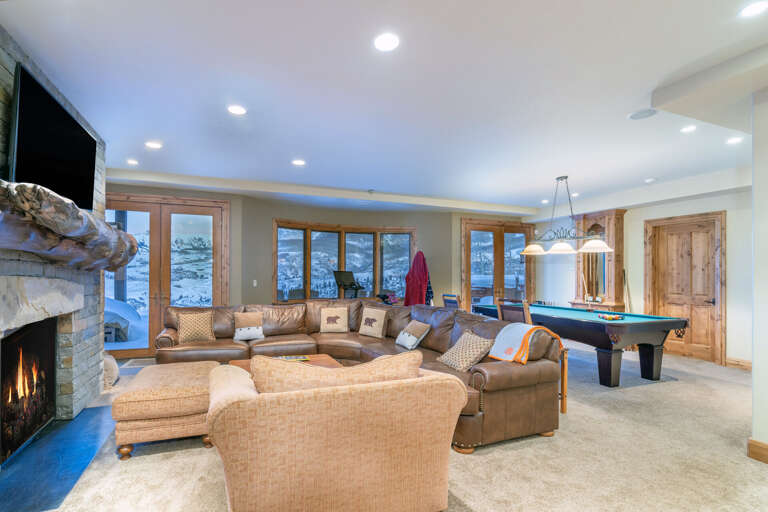 A pool table sits behind a large leather couch in the living area. A pool table sits behind a large leather couch in the living area.