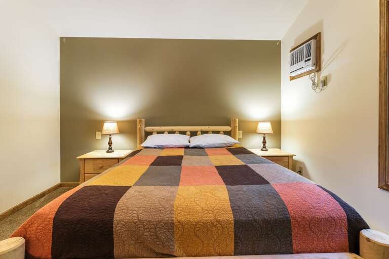 Air conditioner, nightstands, and large bed of rental bedroom.