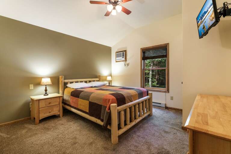 Angled photo of TV, dresser, bed, and nightstands of bedroom.