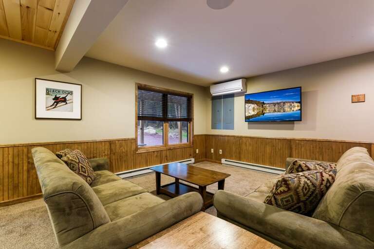 Two couches, coffee table, and TV by the game room.