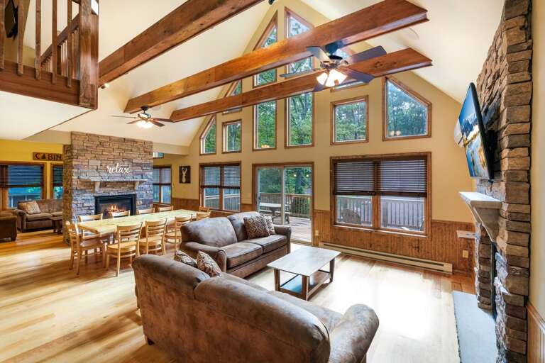 The fireplace, seating, and TV of the great room facing large windows.