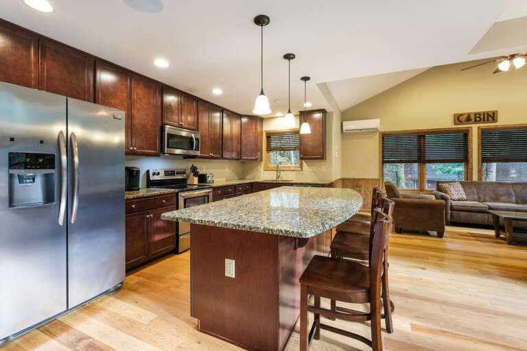 Kitchen island with bar seating, refrigerator, oven, and microwave. Living area seating visible to the right.