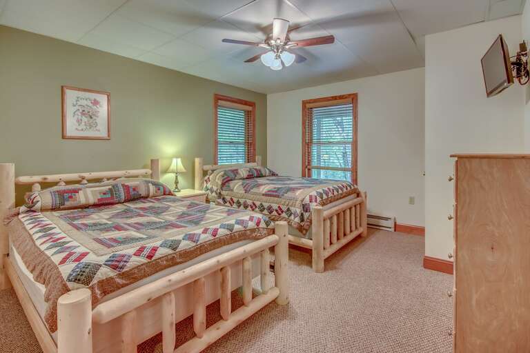 Bedroom with Two Beds, Nightstand, Dresser, Ceiling Fan, and TV.