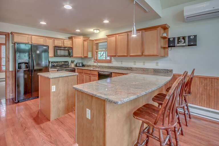 Kitchen with Counter, High Chairs, Refrigerator, Microwave, and A/C.