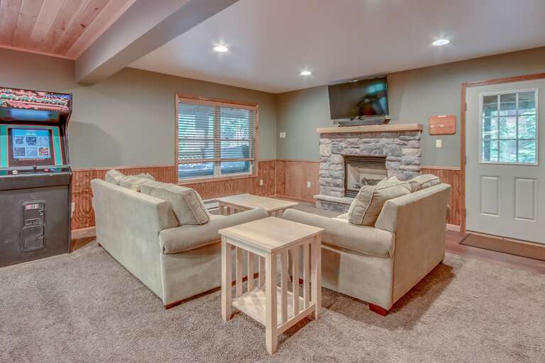Living room with couches, a fireplace and an arcade machine
