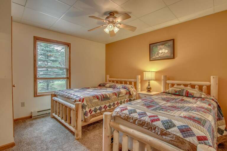 bedroom with tan walls, two beds, and a ceiling fan