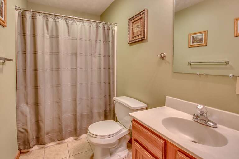A picture of the bathroom with the toilet, sink, and shower (with curtain closed) in shot. A picture of the bathroom with the toilet, sink, and shower (with curtain closed) in shot.