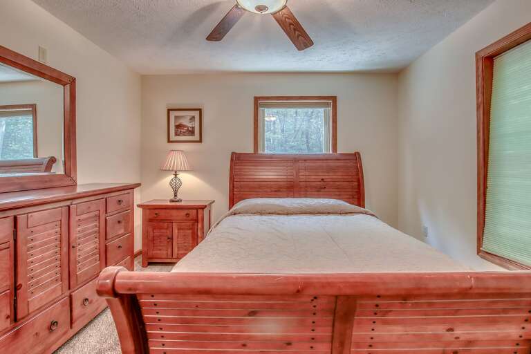 A picture from the foot of a bed, with a nightstand with a lamp beside it and a vanity on the left wall. A picture from the foot of a bed, with a nightstand with a lamp beside it and a vanity on the left wall.