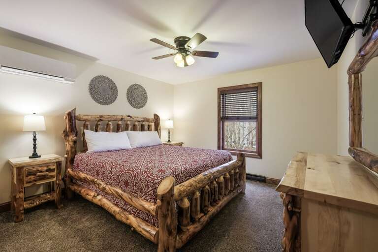 Bedroom with Red Linens, Side Tables and Mounted TV