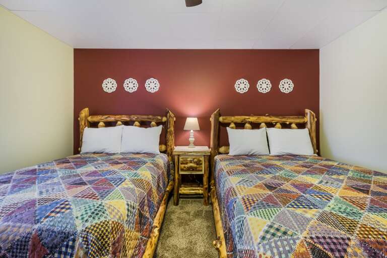 Beds with Patterned Linens in Bedroom with Red Wall
