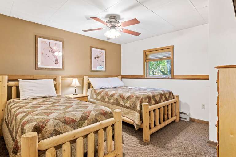 tan bedroom with two beds and ceiling fan