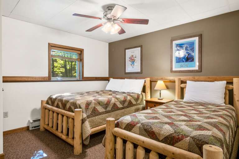 tan bedroom with two beds and pictures on the wall