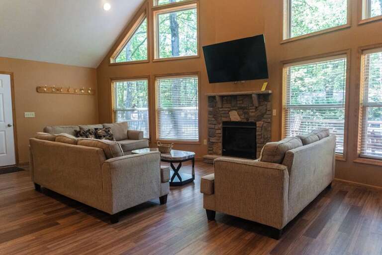 Living Room With Large Windows, Wooden Floors, And A Fireplace In A Serene Setting