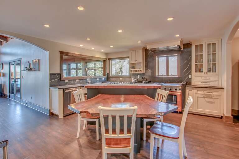 Island table with chairs, cupboard, and wood counter tops of the kitchen.