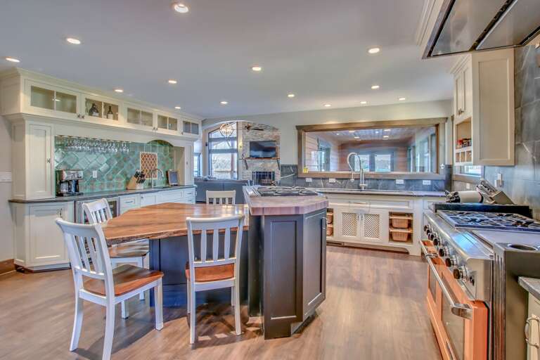 Island with table and chairs in view, oven, and sink of the kitchen.