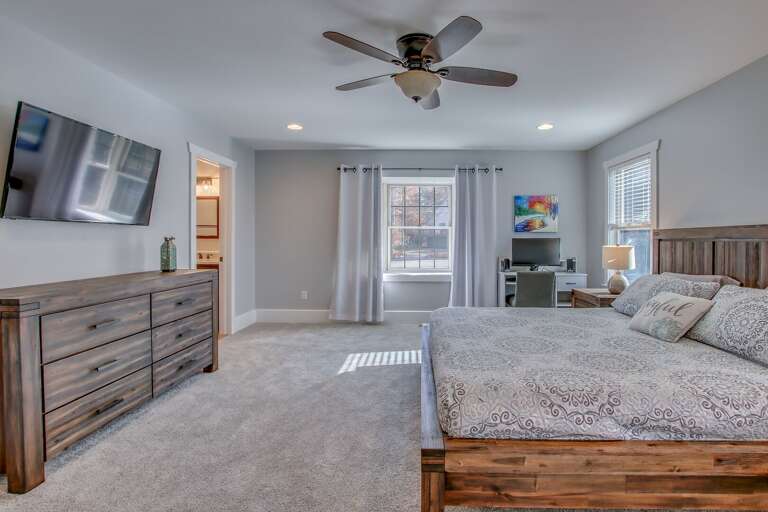 Large bed, computer desk, TV and dresser of master bedroom.