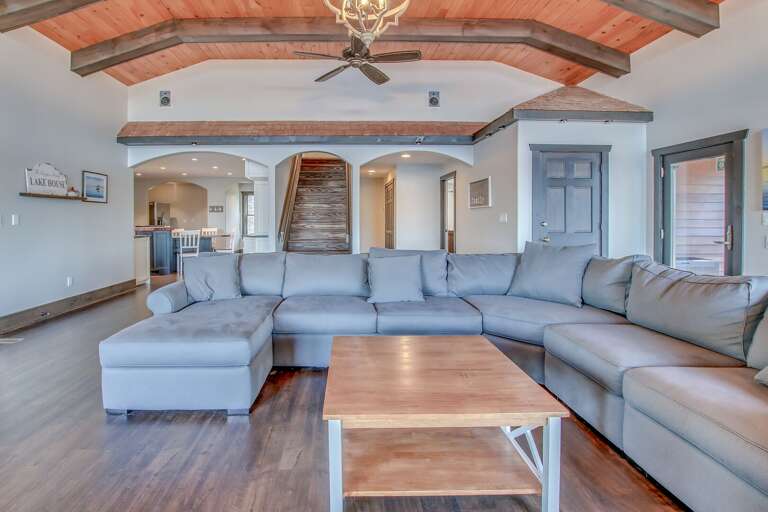 Picture facing the sectional couch and coffee table of the great room, with the entryways to other rooms in the background.