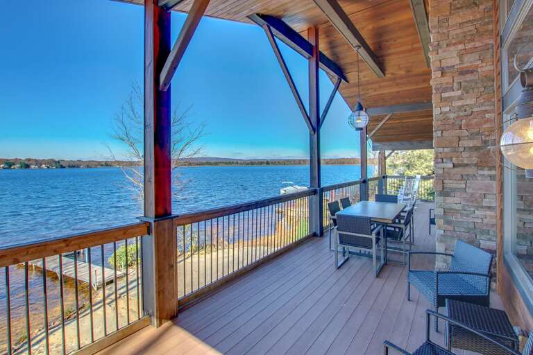 A picture of the lake taken from the back porch, with outdoor furniture and a view of the dock.
