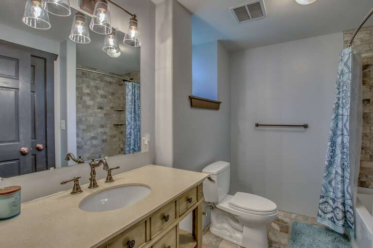 Sink with large mirror, toilet, and shower (with curtain open).