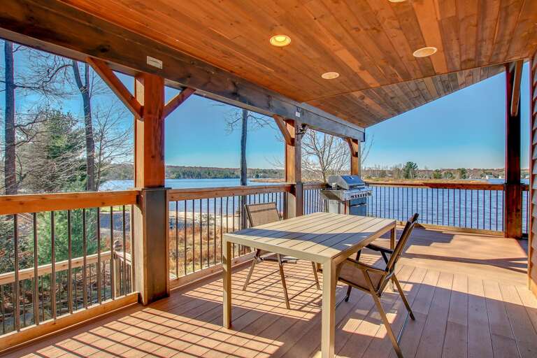 Table and chairs overlooking the lake and surrounding forest from the upper porch.