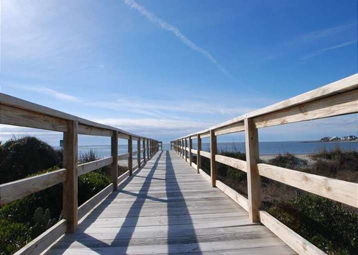 Wooden Boardwalk Leading To Beach Under Blue Sky Wooden Boardwalk Leading To Beach Under Blue Sky
