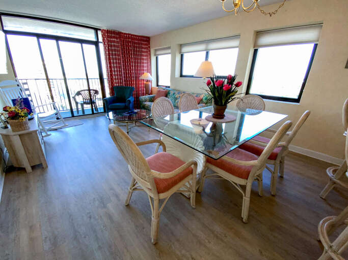 Bright Beachside Room With Glass-top Dining Table And Balcony View