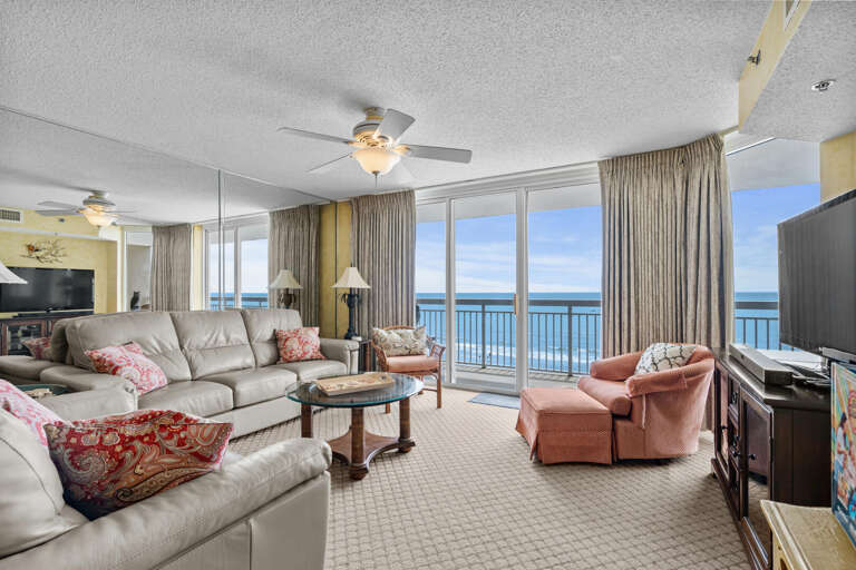 Spacious Seaside Living Room With Plush Seating And Panoramic Ocean View Through Large Windows