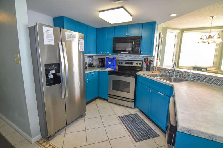 Bright Blue Kitchen With Stainless Steel Appliances And Tiled Floor
