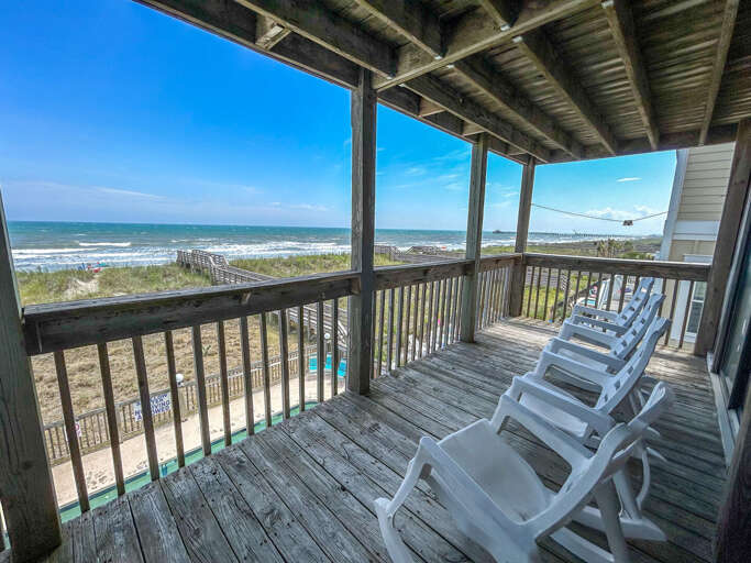 Beachfront Balcony With Rocking Chairs Overlooking The Ocean