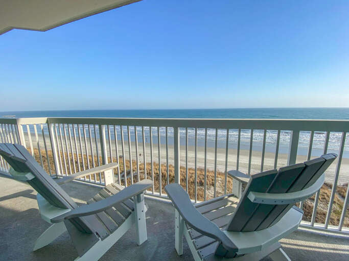 Balcony View With Beach, Blue Sky, And Lounge Chairs