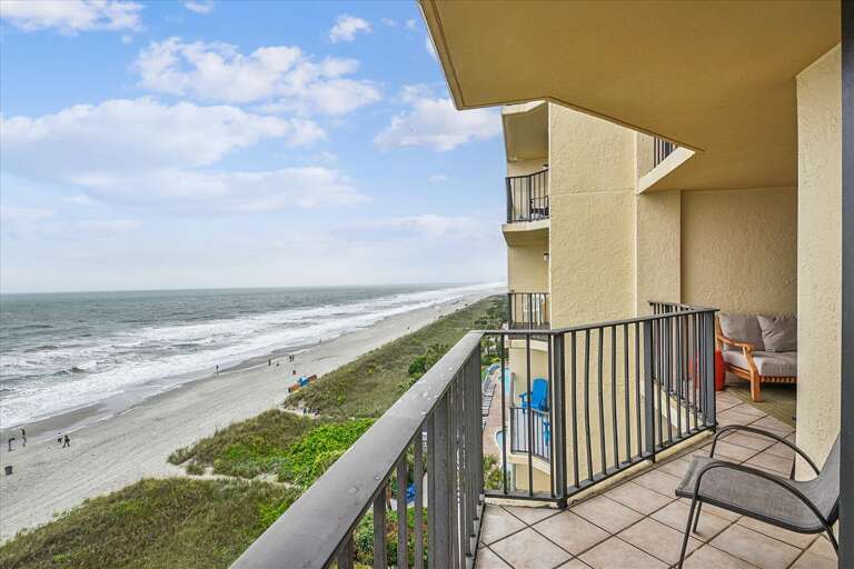 Balcony View Of Beach, Breezy Waves Washing The White Sand Shore