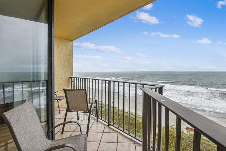 Balcony Overlooking Beach With Chairs And Railing