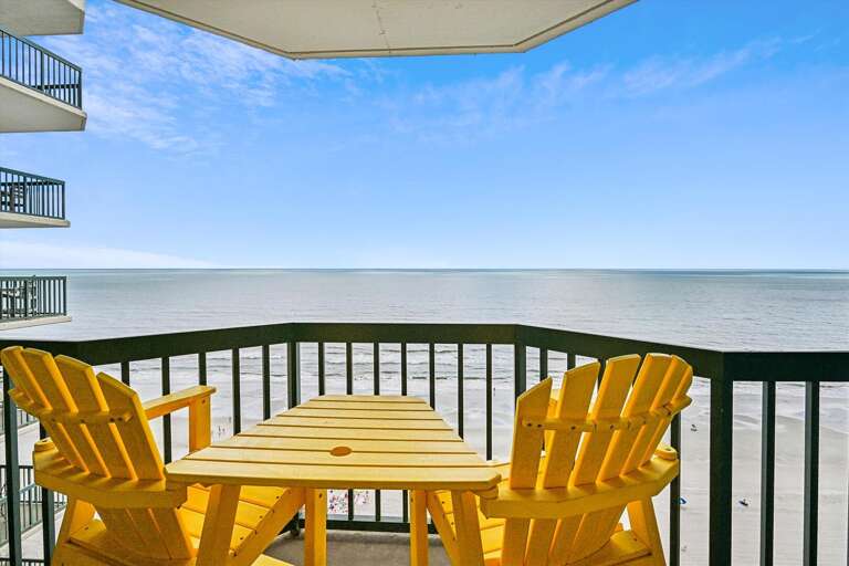 Balcony View With Bright Chairs Facing The Sea At A Vacation Rental