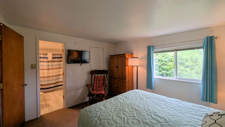 queen bedroom with TV, wardrobe &amp; rocking chair.