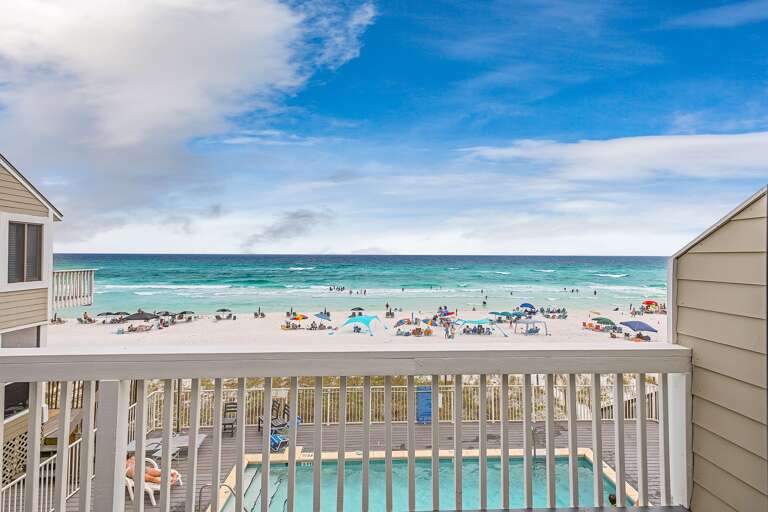 Breezy Balcony View Overlooking Vibrant Beach Scene With Sunlit Sea