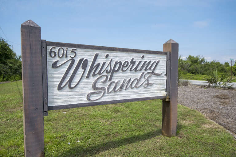 Wooden Sign Whispering Sand Standing Sharply Against A Soft Sky
