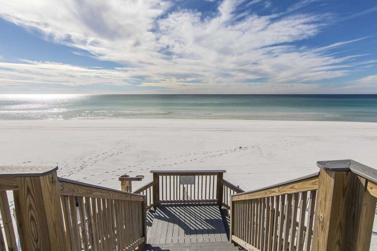 Seaside Staircase Steps To Serene Sandy Shore Under Shimmering Sky