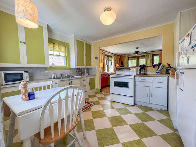 Cook your favorite meals in this charming retro kitchen with cheerful green checkered floors, white appliances, and cozy breakfast nook.