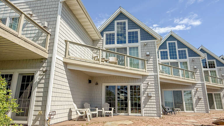 Charming coastal architecture with classic shingle siding, spacious balconies, and large windows welcoming abundant natural light into this inviting retreat.