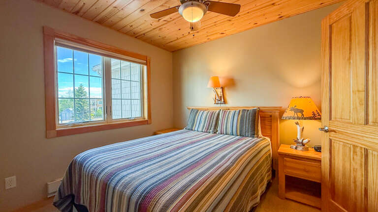 Drift off in this cozy bedroom where rustic wood meets comfortâyour mountain retreat awaits beneath warm timber ceilings and soft bedding.
