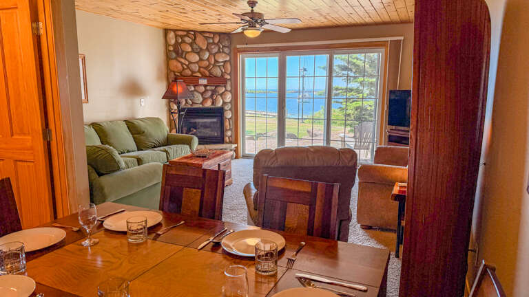 Picture yourself unwinding by the stone fireplace after a day of lakeside adventures. The spacious living and dining areas flow seamlessly, with glass doors opening to your private waterfront view.