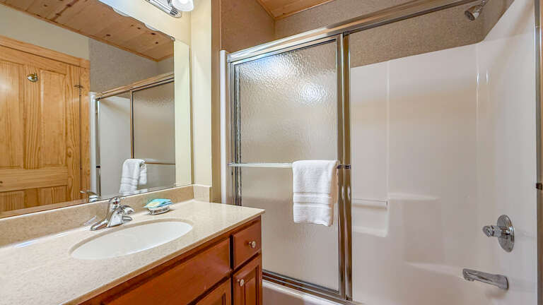 Your private bathroom features a clean shower-tub combo with glass doors and a spacious vanity with a large mirror, perfect for getting ready each morning.