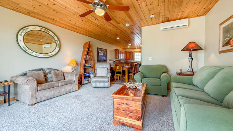 Sink into plush sofas under the warm glow of a vaulted cedar ceiling, where your living and dining spaces flow together in inviting comfort.