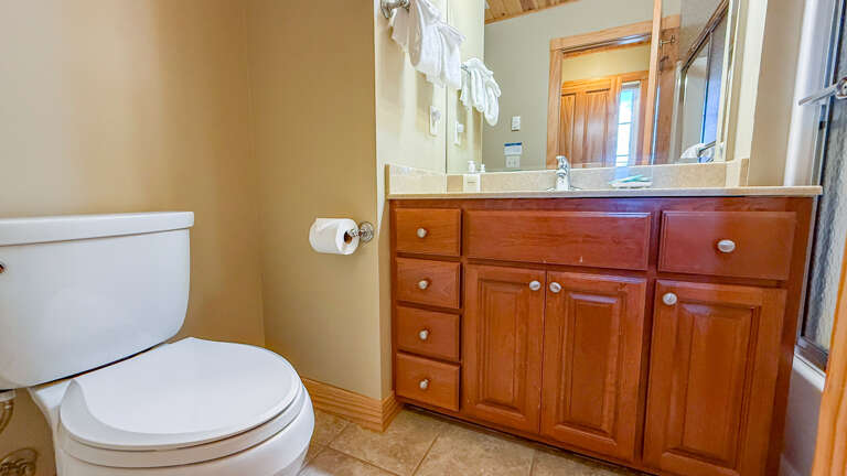 Your spacious bathroom features warm wood cabinetry, generous counter space, and fresh towels waiting for you after a relaxing day exploring the area.