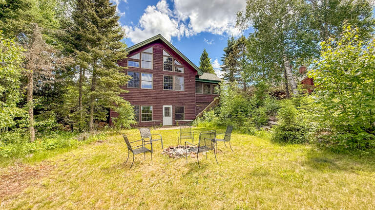 A charming three-story retreat nestled among towering evergreens and lush greenery, offering a peaceful escape in a scenic natural setting.