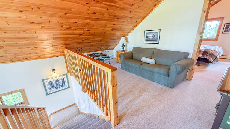 Your cozy loft retreat features warm wood ceilings, a plush sofa perfect for unwinding, and charming details that invite relaxation after a day of adventure.