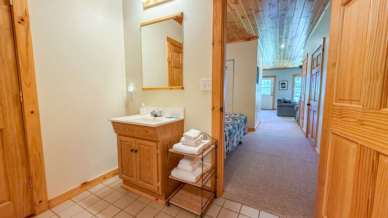 Step into your private retreat with a convenient vanity and fresh towels ready, leading to a cozy bedroom and bright living space where relaxation awaits.