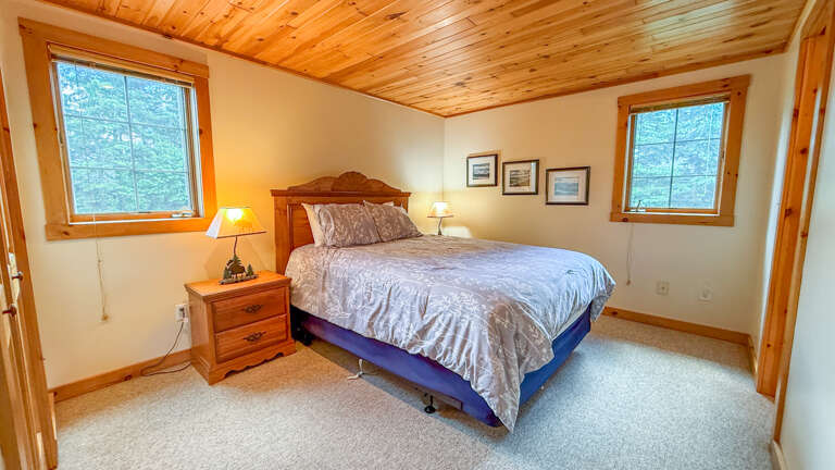 Drift off in this peaceful bedroom with its inviting queen bed, warm wood accents, and views of the surrounding treesâyour perfect retreat after a day of adventure.