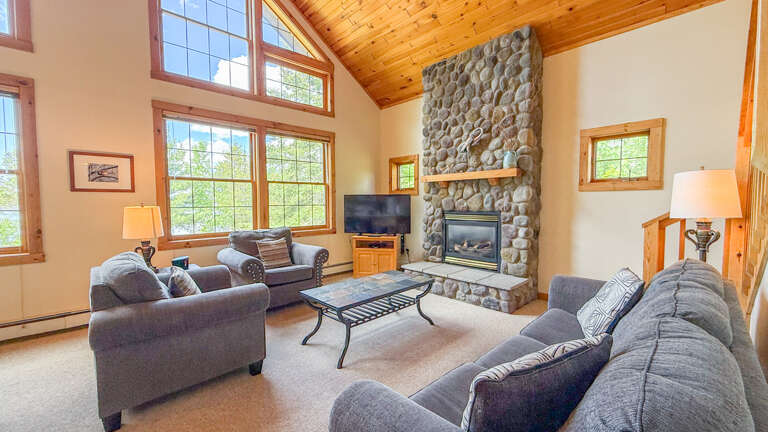 Gather with your group in this bright, open living room featuring vaulted wood ceilings, a dramatic stone fireplace, and plush seating that invites relaxation after a day of adventure.