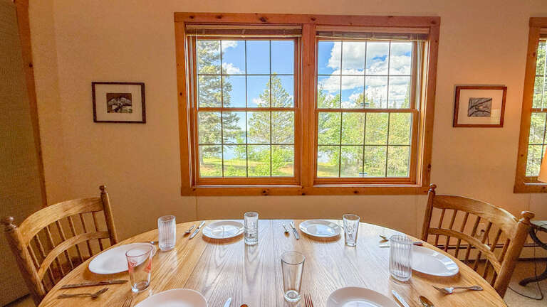 Gather around this inviting wooden table where your group can share meals while enjoying views of the surrounding landscape through bright, sunlit windows.